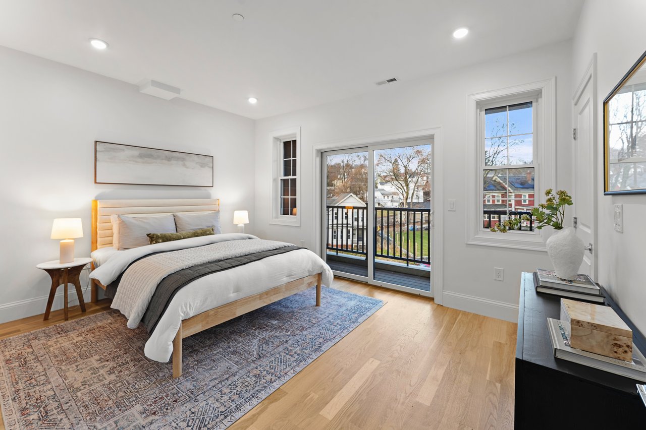 Staged bedroom with a king-size bed and sliding glass door to a balcony.
