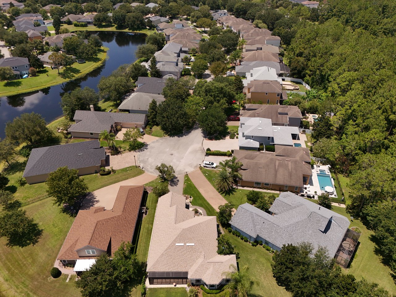 Austin Park homes surrounding a pond and circular street, with mature trees and a backyard pool.
