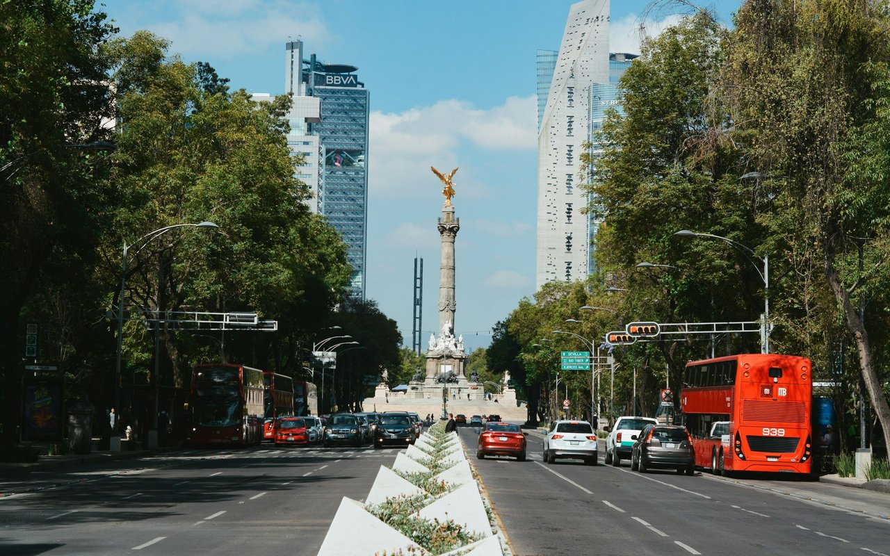 Mexico City’s Paseo de la Reforma, with the Angel of Independence monument, traffic, and red buses.