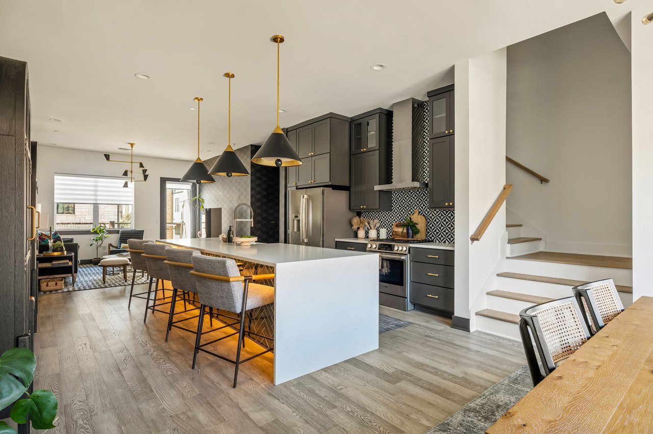 Kitchen, dining, and staircase view at 4507 Unity Circle in The Grove, Austin, showing the open floor plan and pendant lighting, upgrades by Ashley Walker Designs.