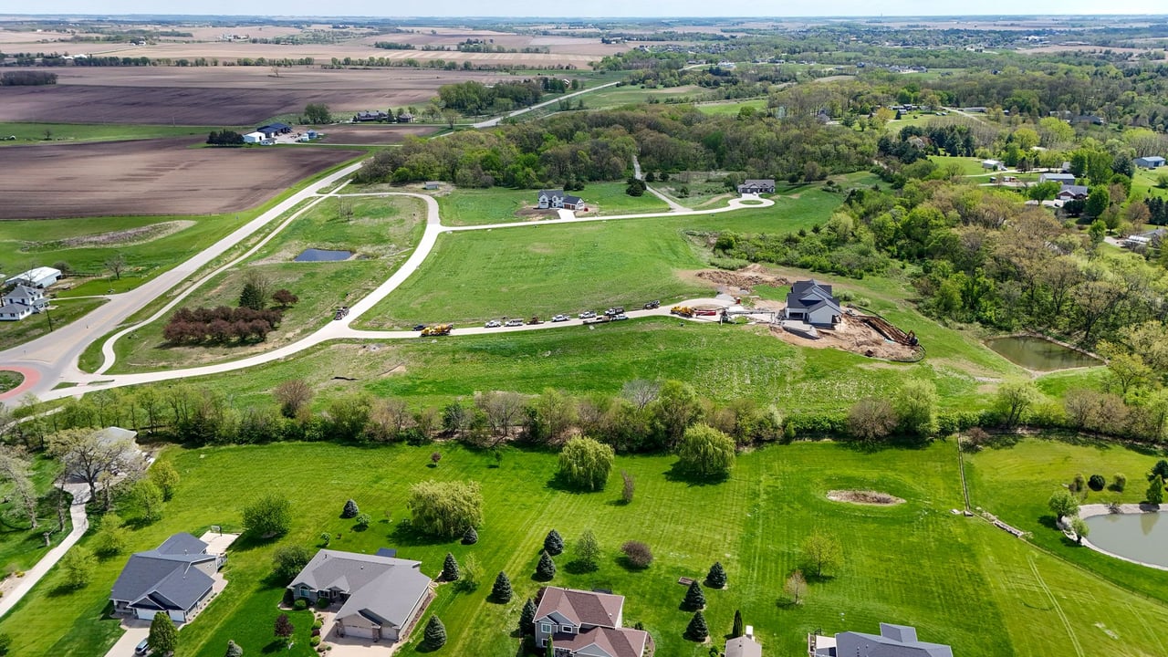 Aerial view of Oak Meadow’s curving roads, green lots, and a home under construction.