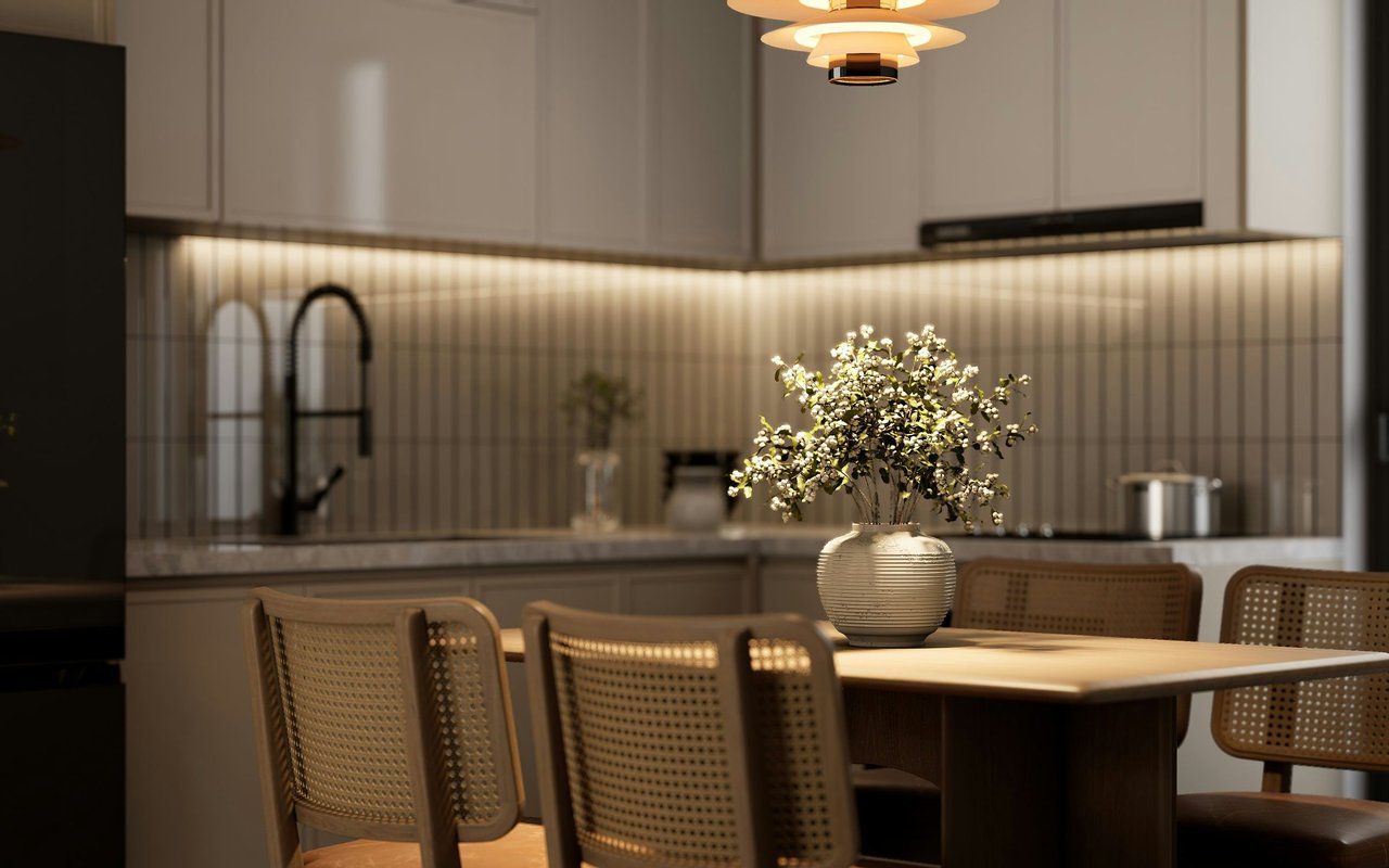 Kitchen and dining area with pale cabinets, cane-backed chairs, and flowers on the table.