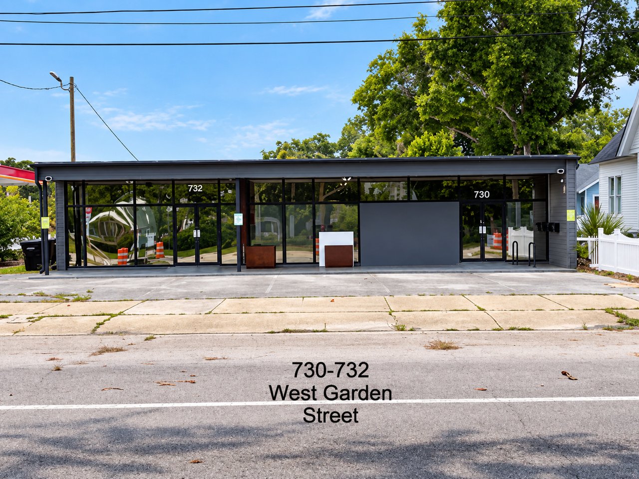 Modern dark storefront at 730–732 West Garden Street, with broad glass windows and a paved forecourt.