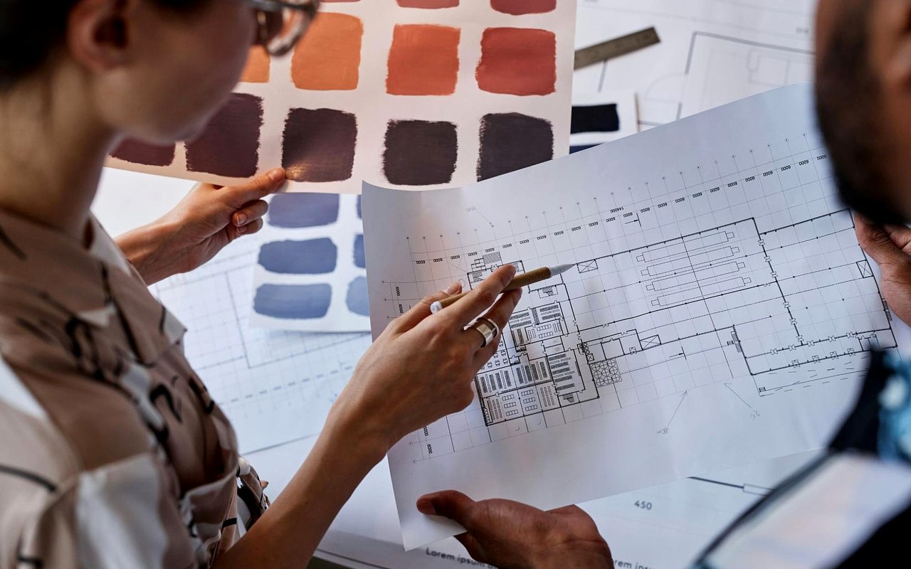 Two people review a floor plan beside paint color samples.
