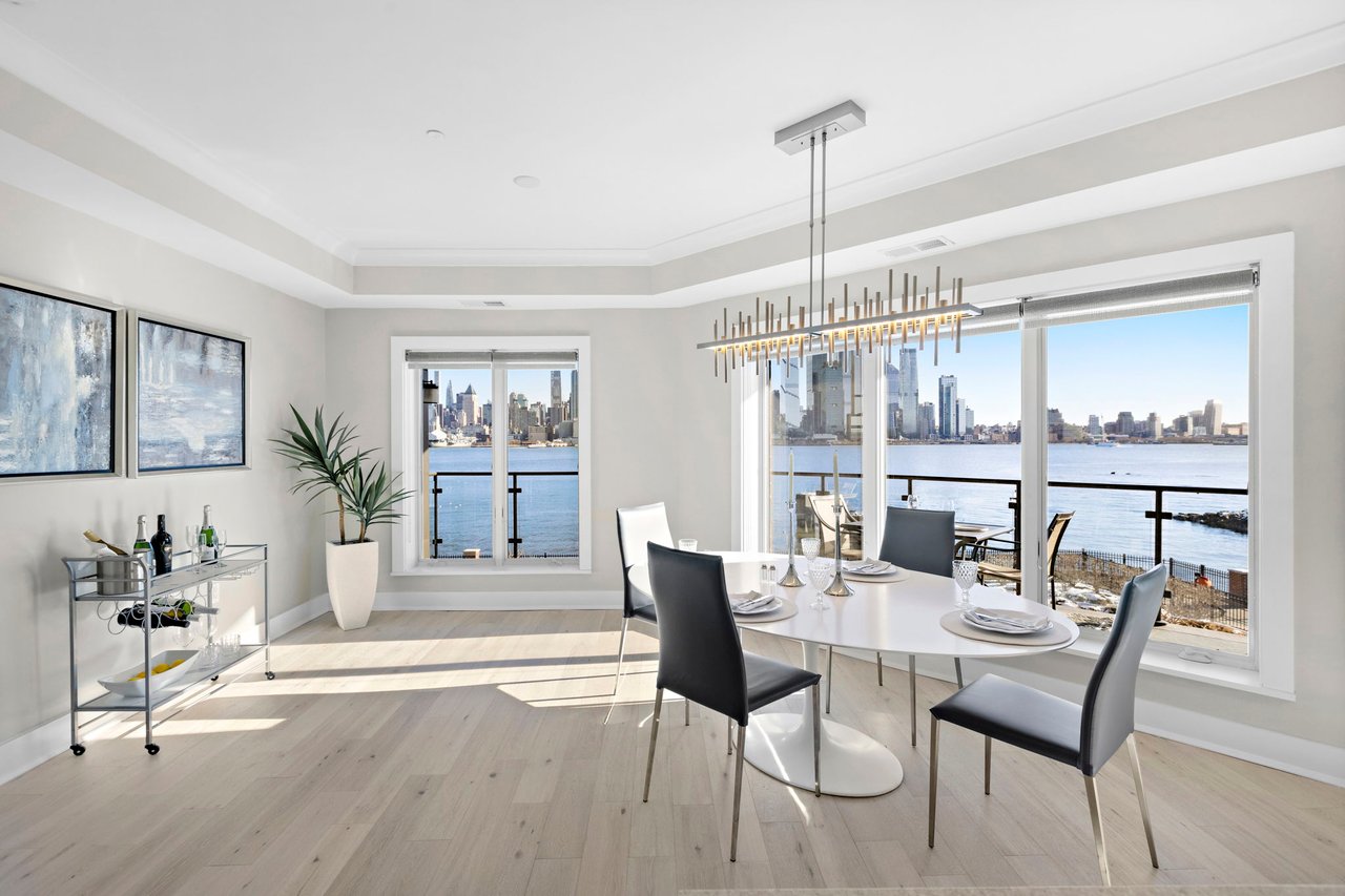 Dining table set near a window offering picturesque waterfront and city views