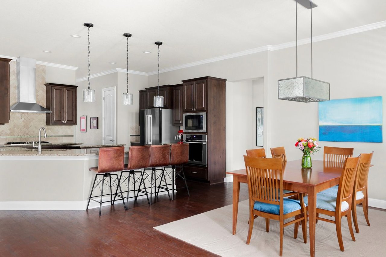 Kitchen and dining area with dark cabinetry, stainless steel appliances, and a large island with bar stools.