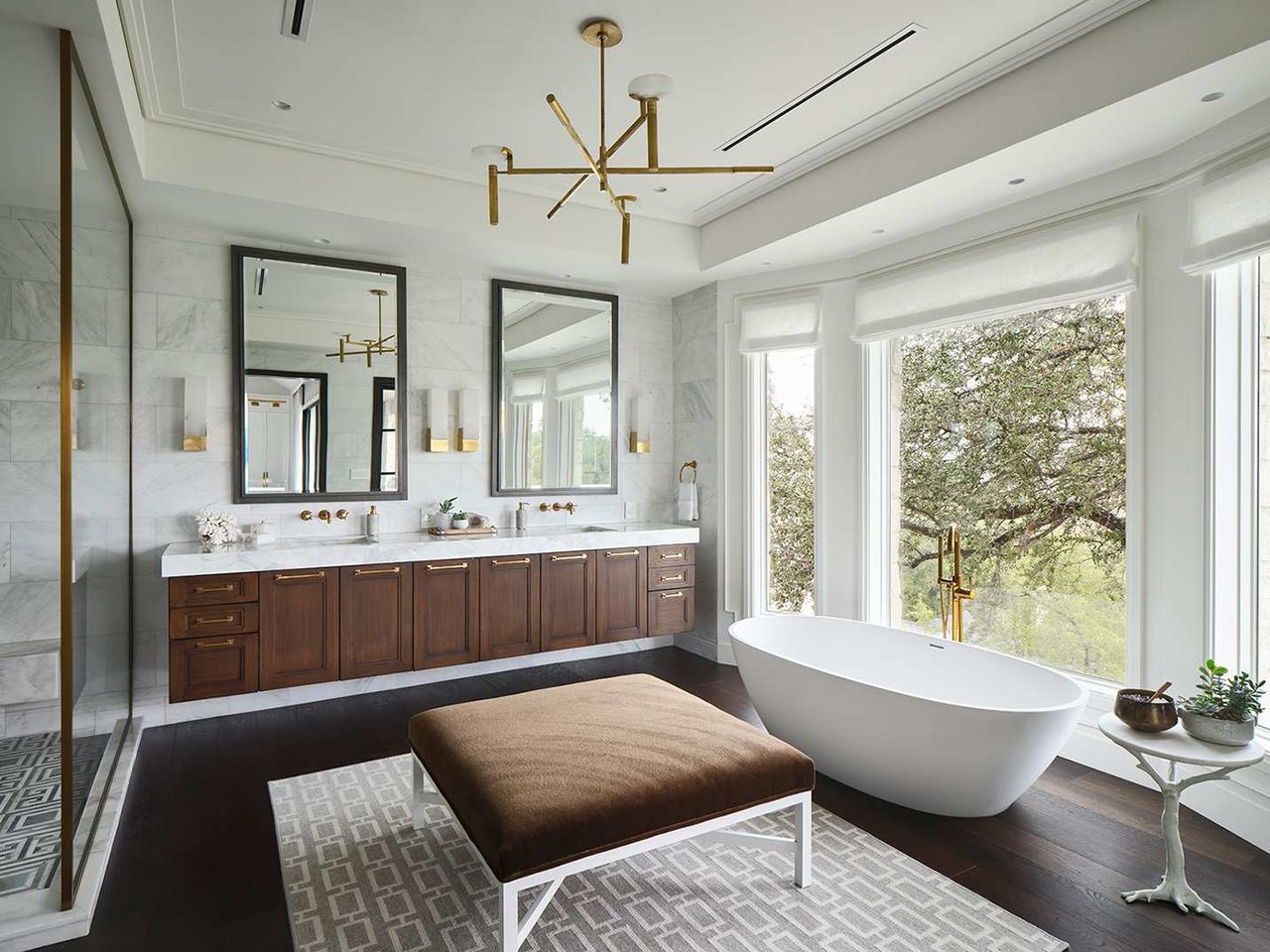 Primary bath with honed marble to the ceiling, a freestanding soaking tub and wall-mounted brass fixtures, 4408 Long Champ Dr, Lake Austin.