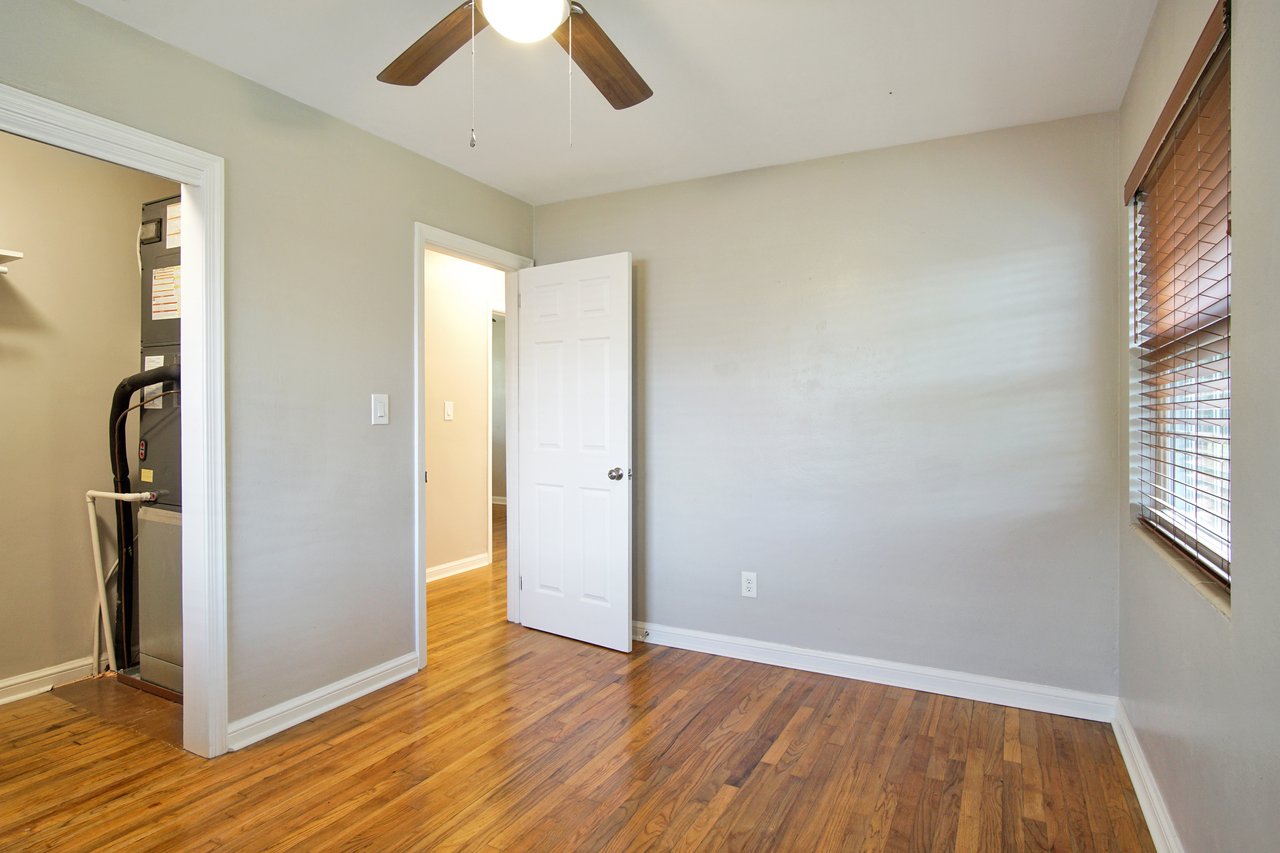 A room featuring a ceiling fan and a door, showcasing a simple and functional interior design.