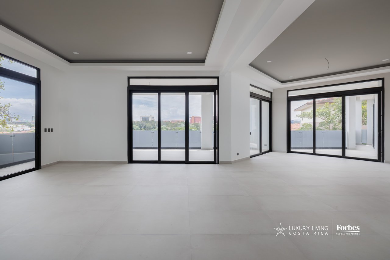 Empty apartment living area with black-framed sliding glass doors opening onto balconies.