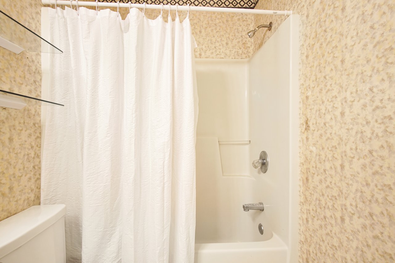 A clean bathroom featuring a shower, toilet, and sink, designed for functionality and comfort.