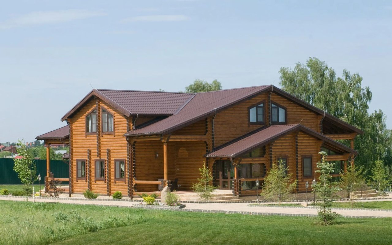 Two-story log cabin with multiple gabled roofs, a covered porch, and landscaped grounds.
