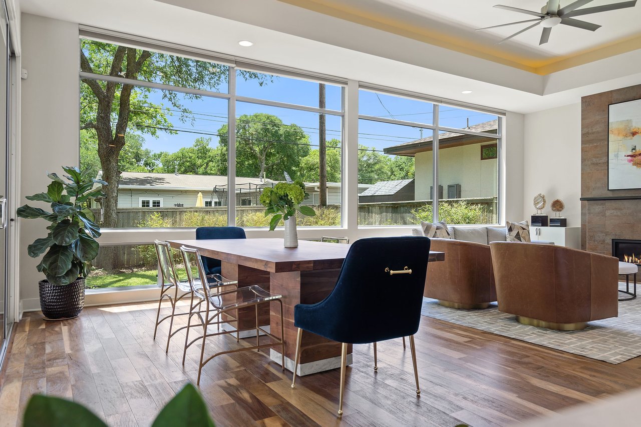 Open dining and living area with a tray ceiling and fireplace at 34 Margranita Crescent, Tarrytown, Austin, TX.