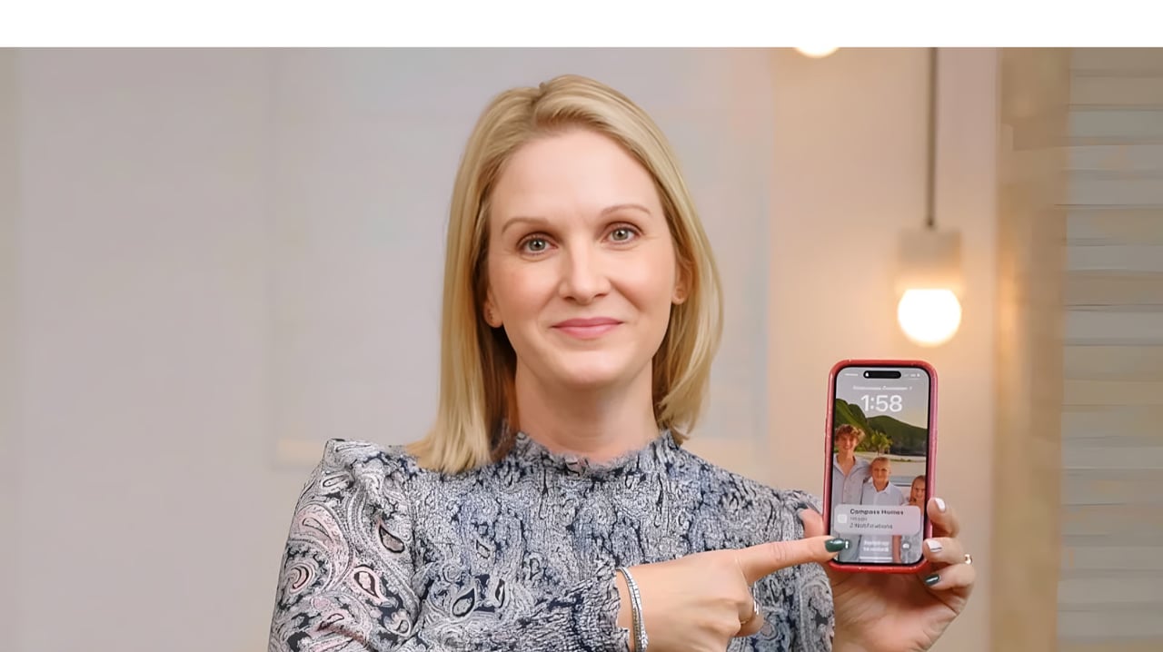 A smiling blonde woman holding a red phone case and pointing at the screen, which shows a photo and a notification.
