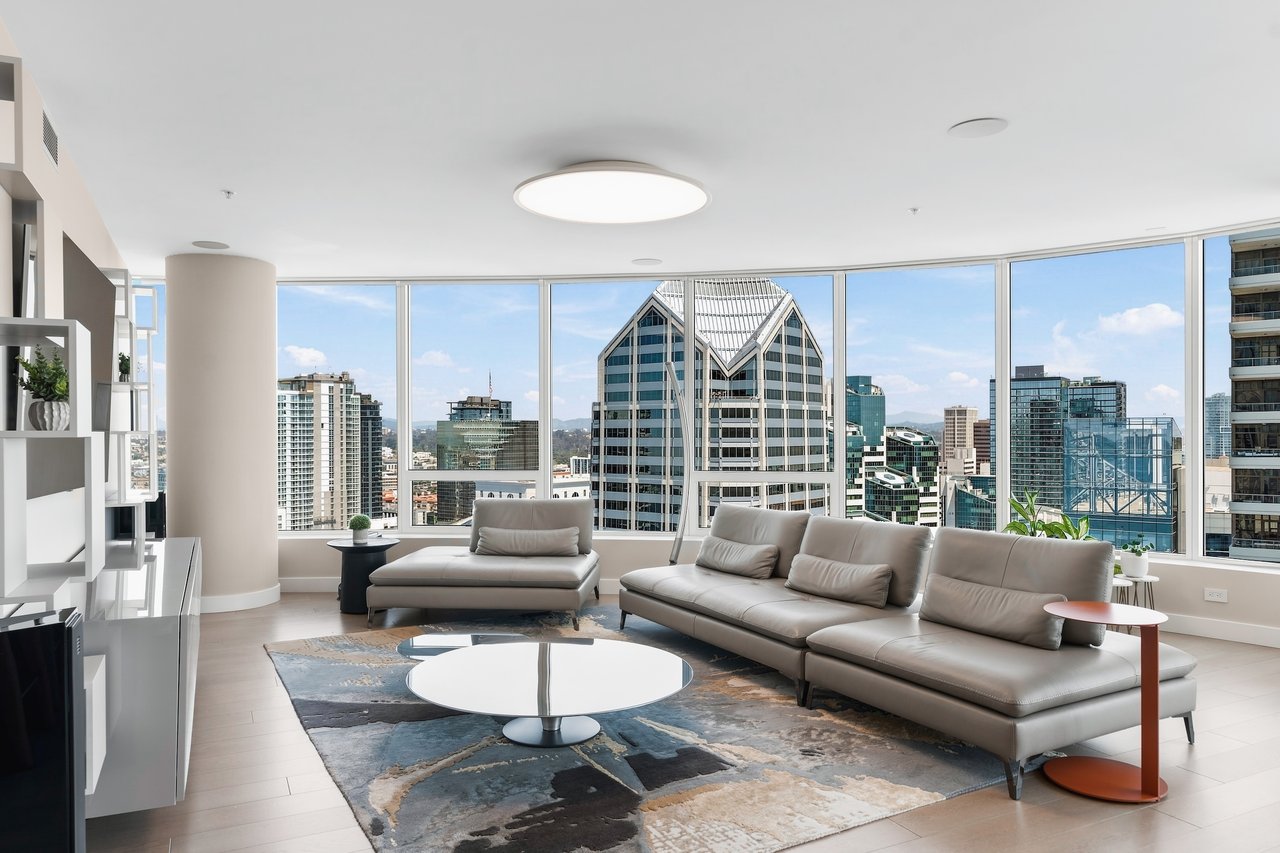 High-rise living room with a gray sectional and floor-to-ceiling windows overlooking the downtown skyline.