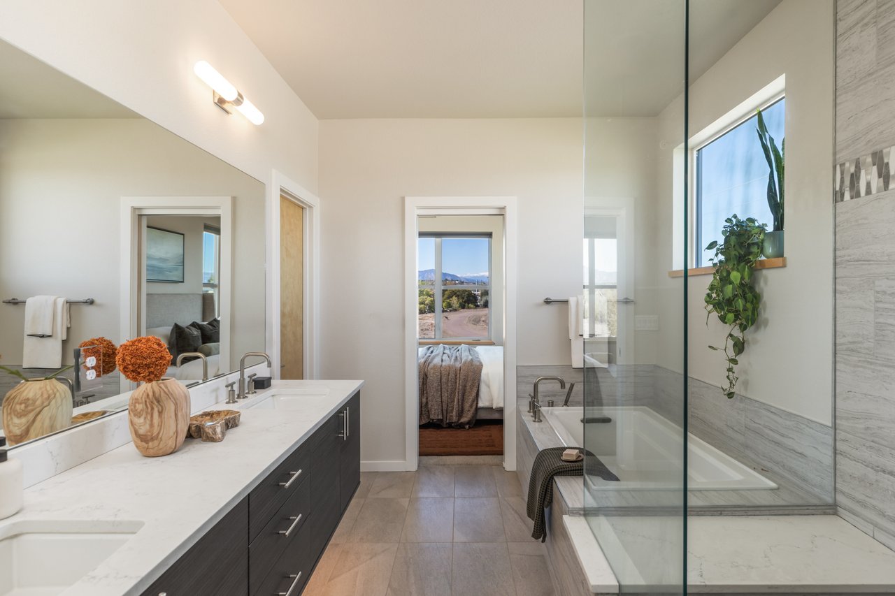 Primary bathroom double vanity with a soaking tub and a doorway into the bedroom