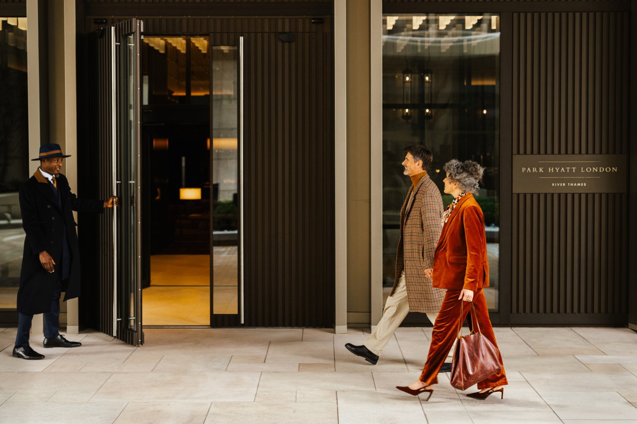Park Hyatt London entrance with a doorman greeting a couple beside the glass doors.