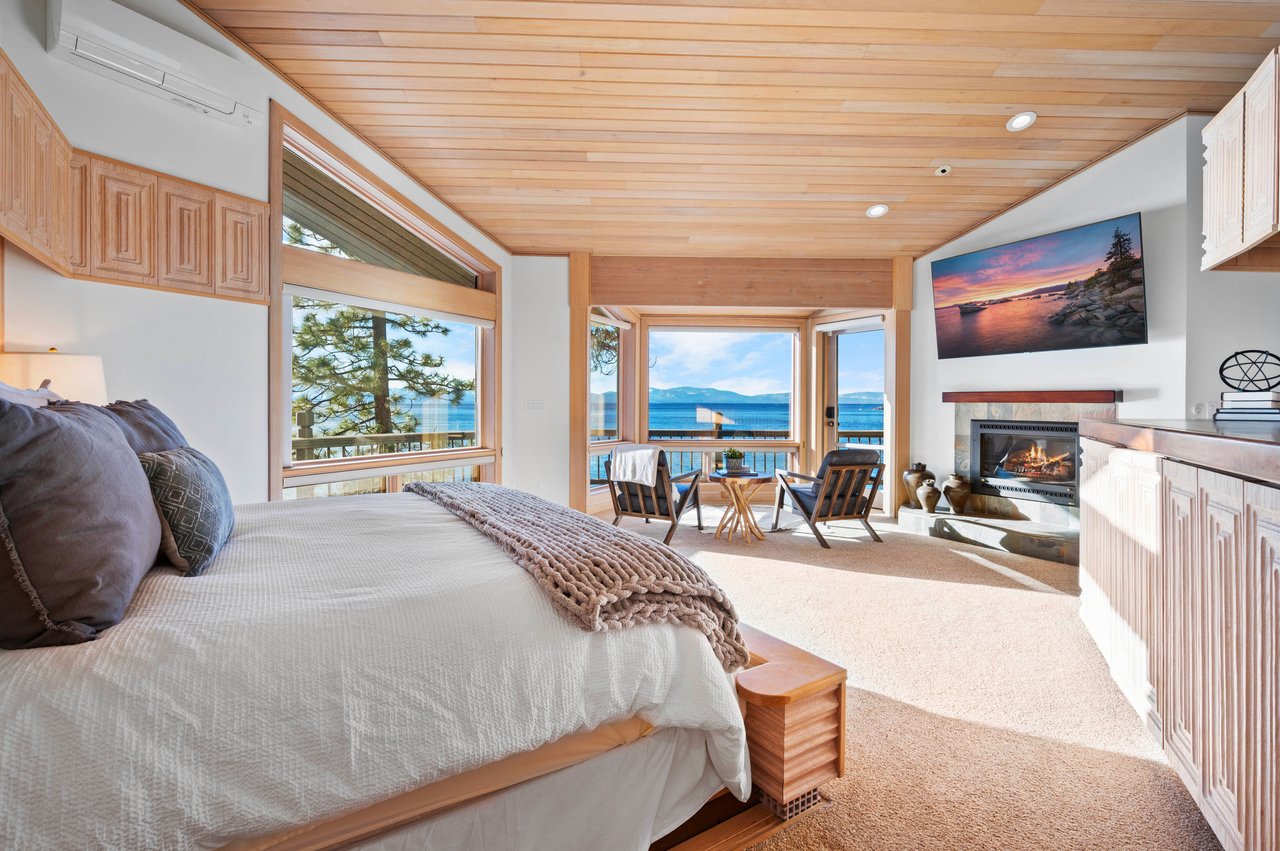 Bedroom with a wood-paneled ceiling, lake views, and a fireplace.