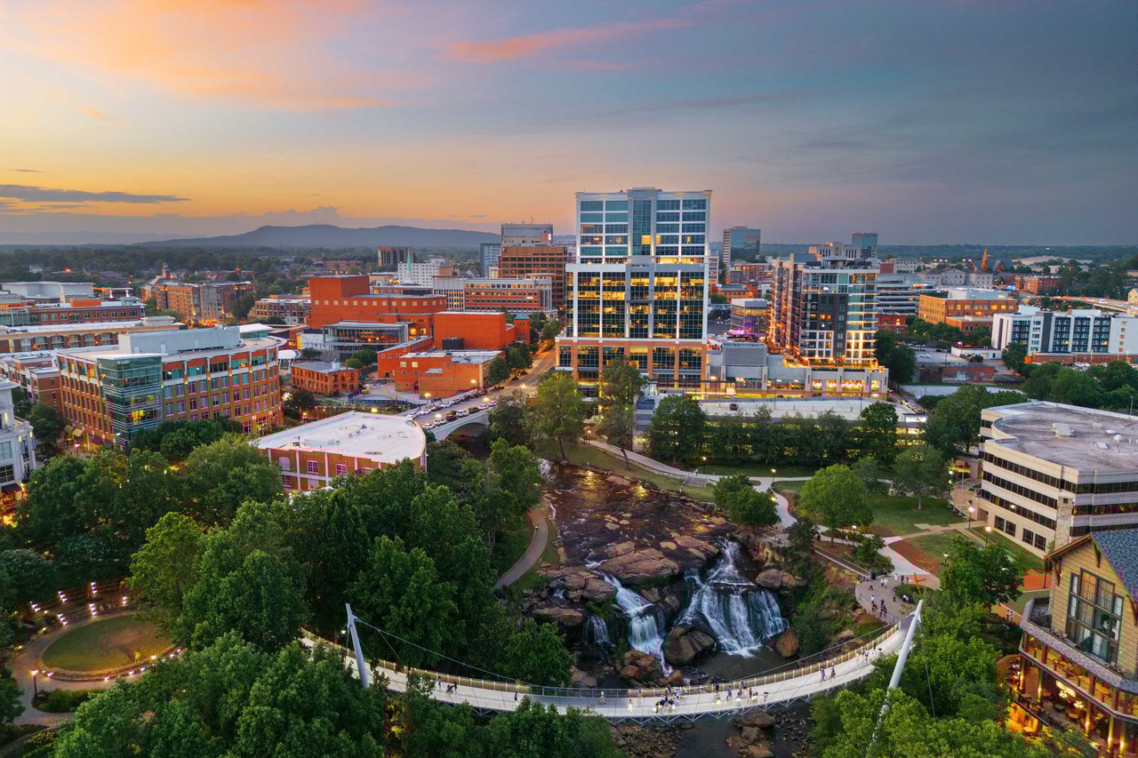 aerial view of a city skyline at sunset with walking bridge and waterfalls