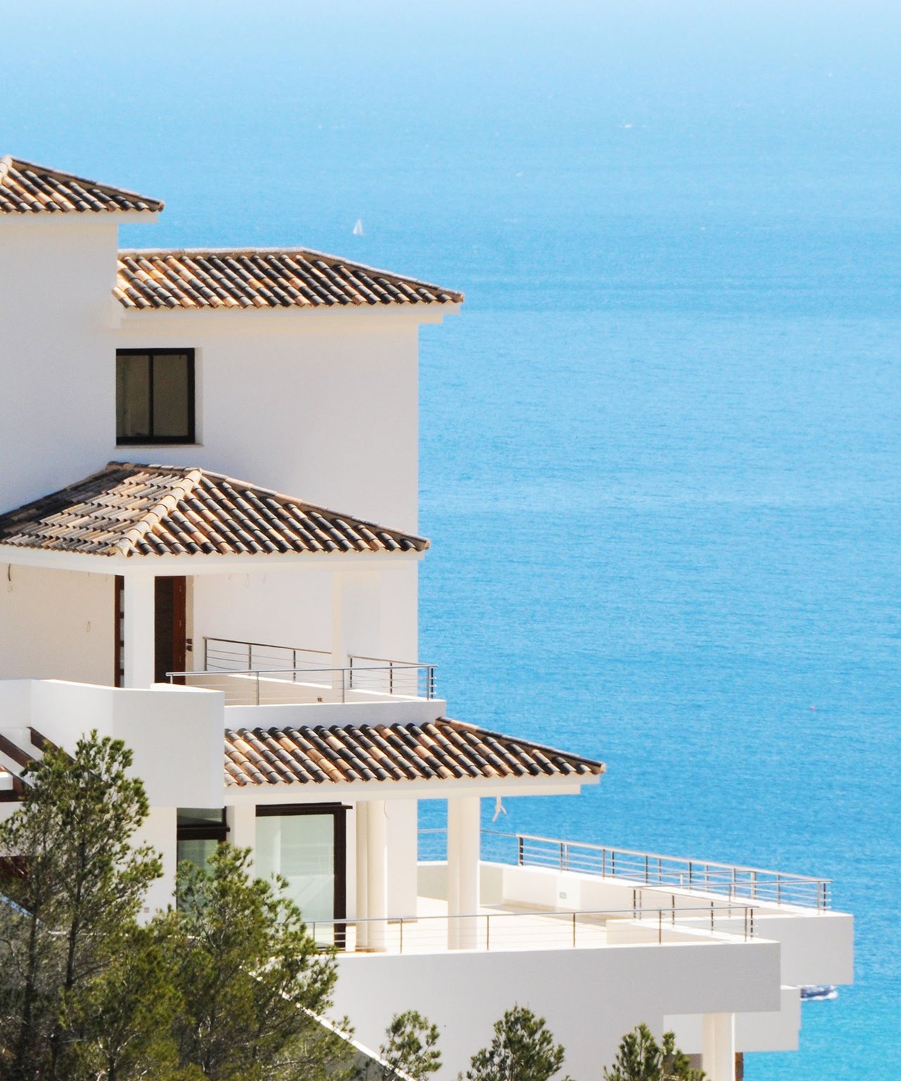 White coastal residence with tiled roofs and terraces overlooking the sea.