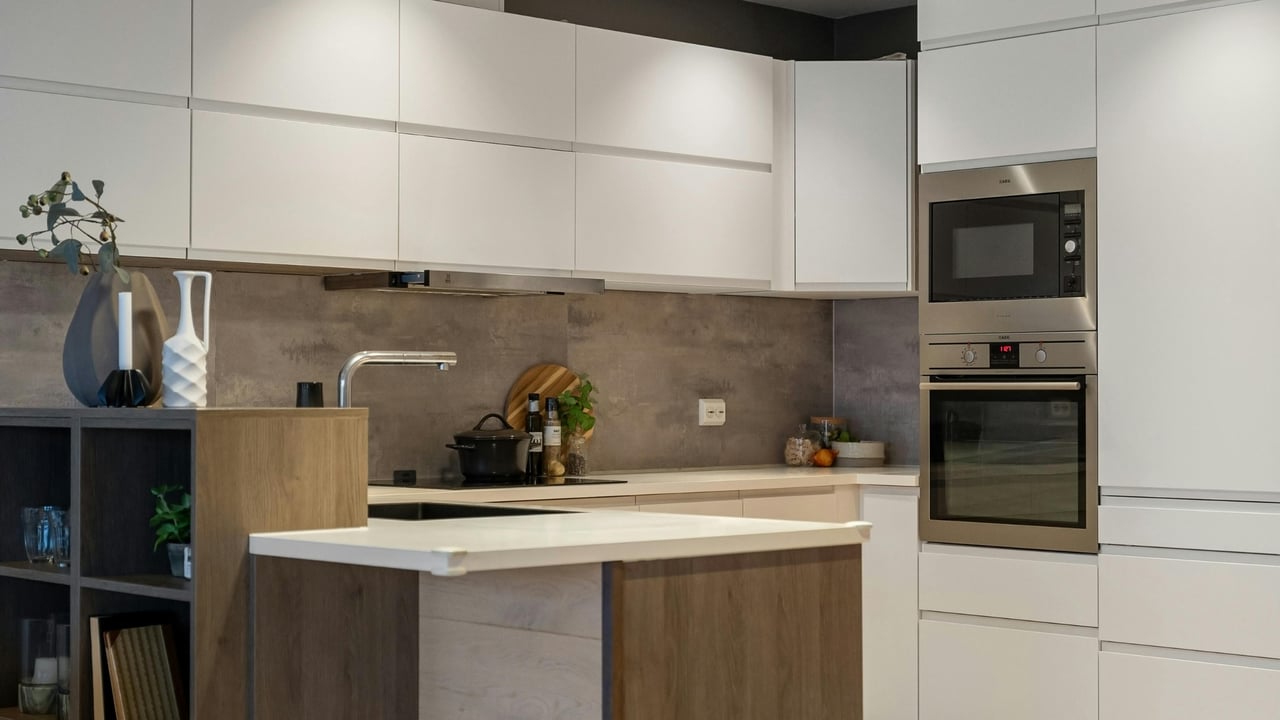 Modern kitchen with white cabinets, a wood-front island, and built-in microwave and oven.