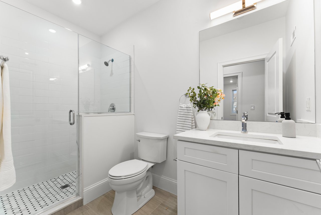 Bathroom with a glass walk-in shower and a white vanity beneath a large mirror.