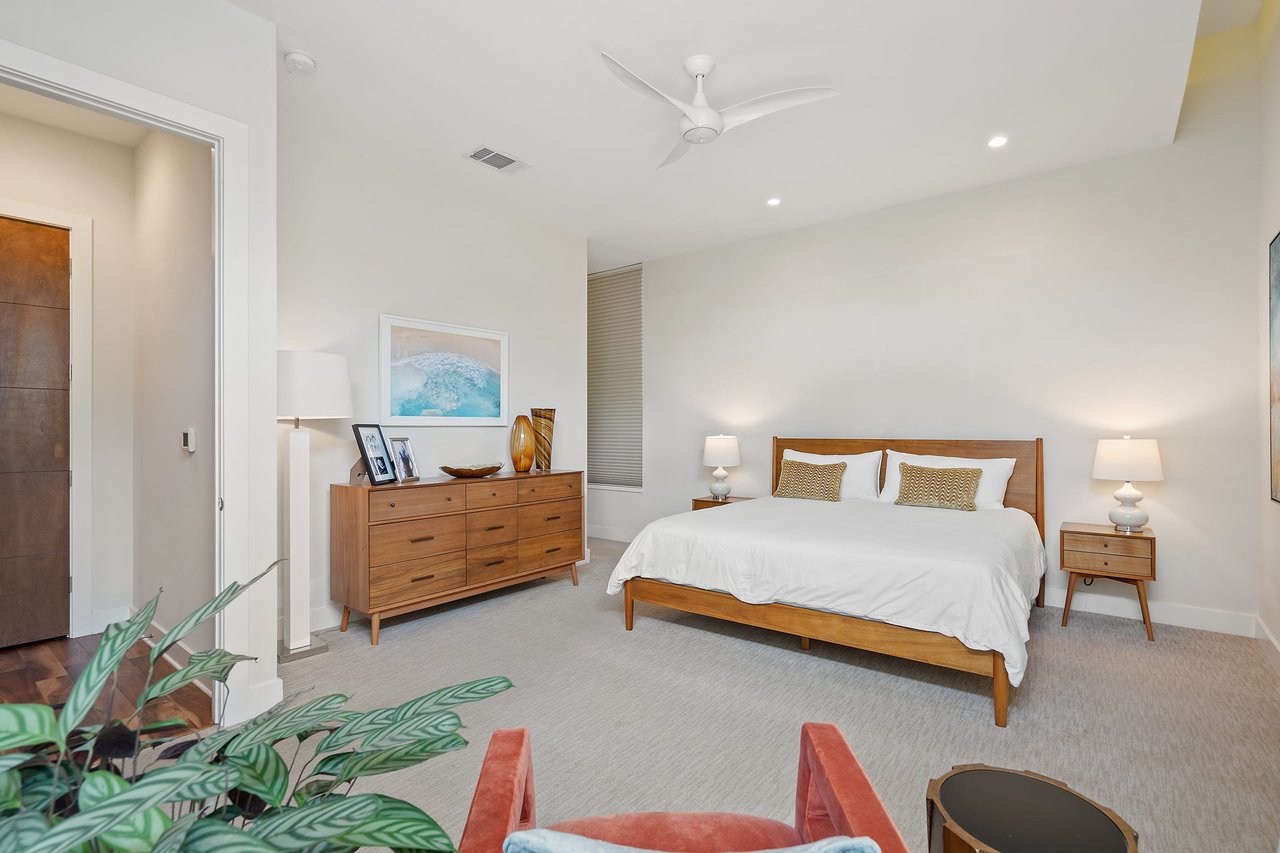 Primary bedroom at 34 Margranita Crescent, Tarrytown, Austin, TX, furnished with wood furniture in a neutral palette over carpet flooring.
