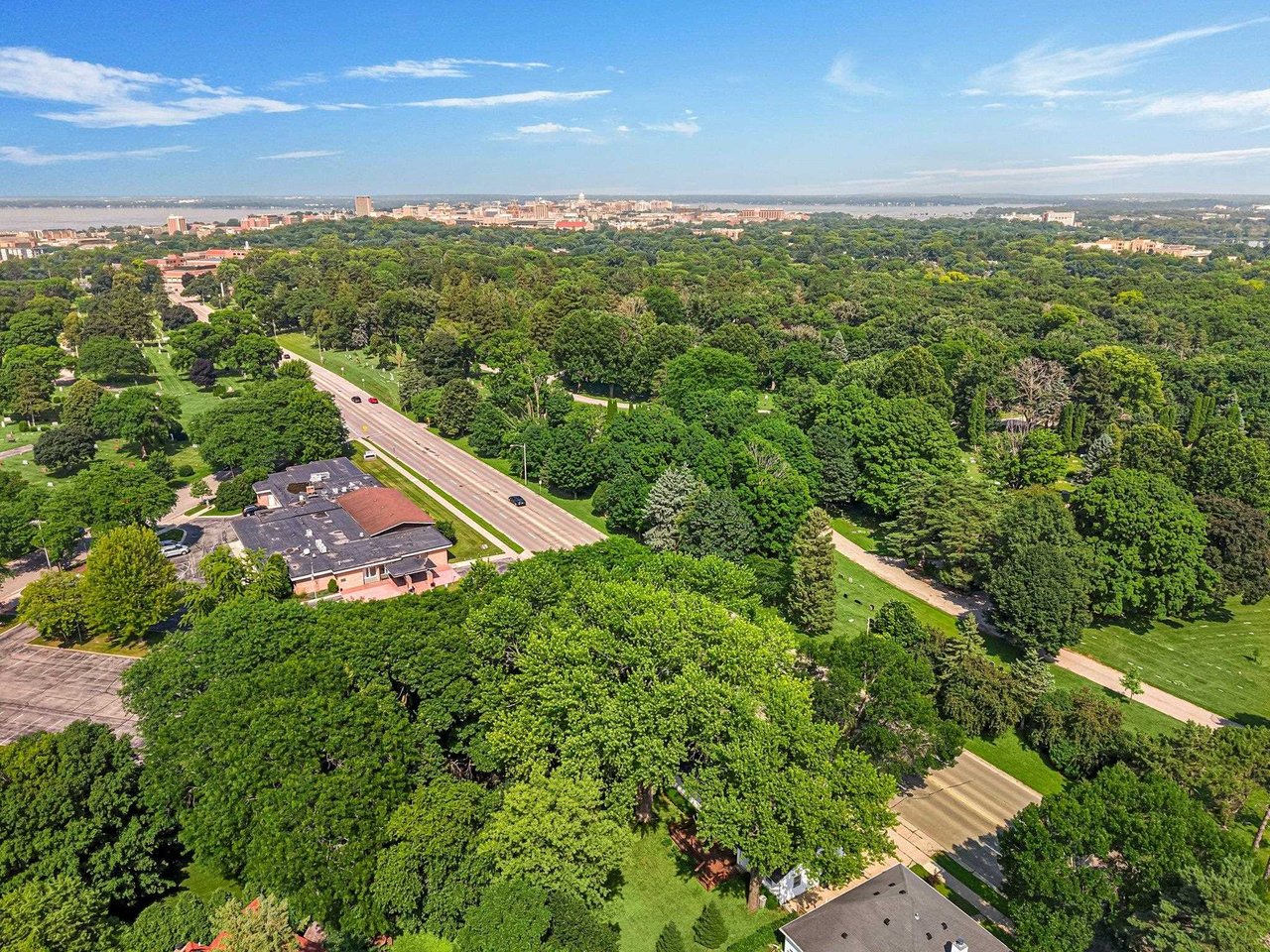 Aerial view of tree-filled Madison, WI neighborhoods with the State Capitol and downtown skyline in the distance.