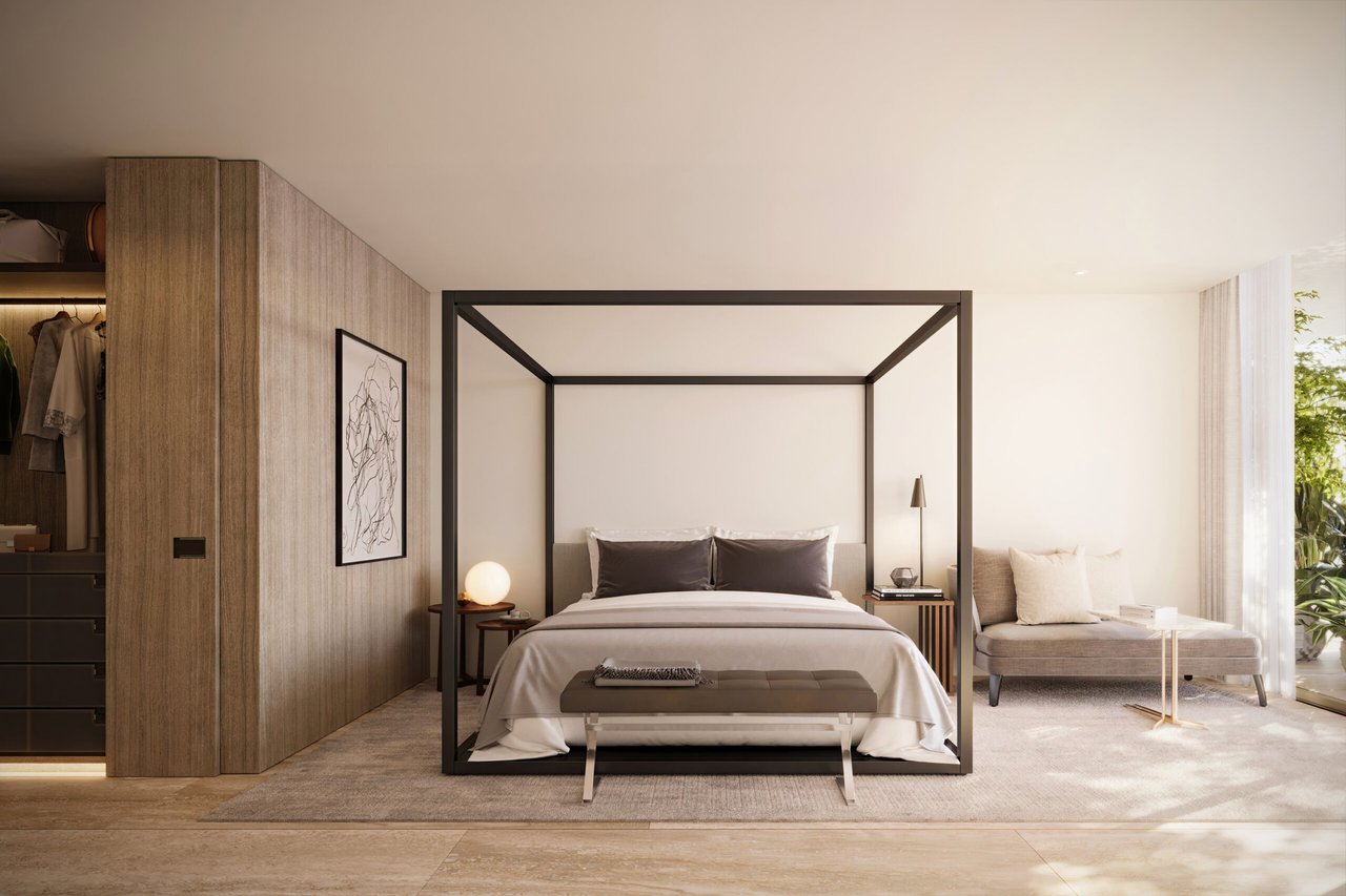 Bedroom with a black-framed four-poster bed, wood-paneled closet, and chaise beside a large window.