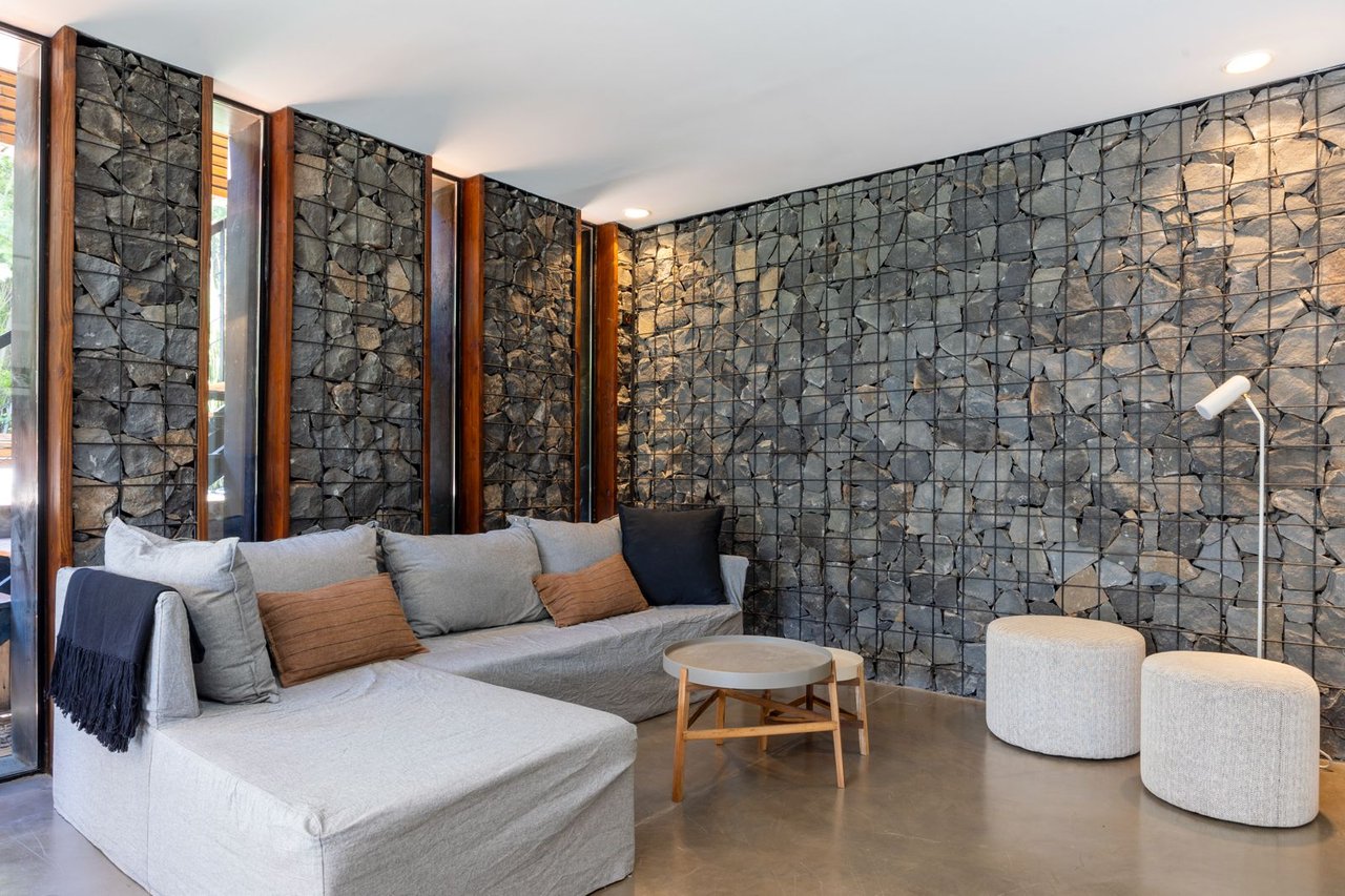 Living room with a gray sectional sofa and distinctive stone-filled wire walls.