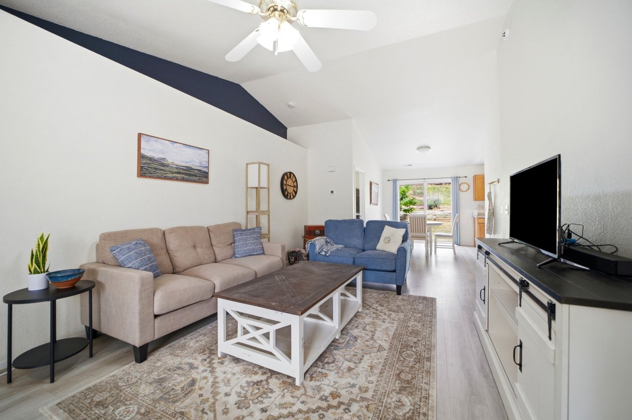 Open living room with sectional sofa and vinyl plank flooring, opening to the dining area