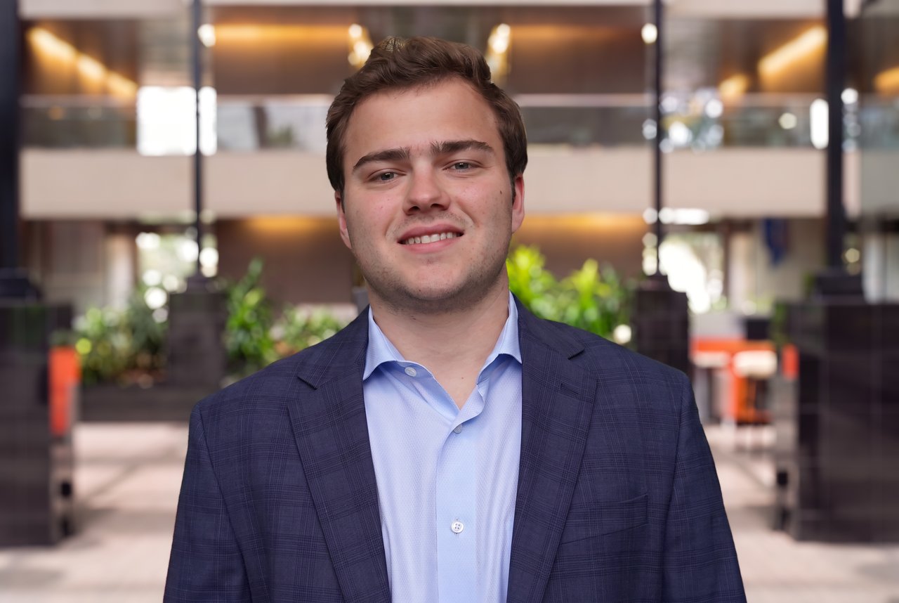Chris Grow in a navy blazer and light blue shirt in a modern office atrium.
