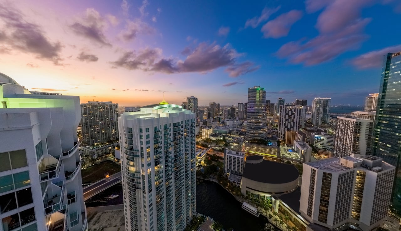 Brickell skyline at dusk, with high-rise buildings along a waterfront beneath a pink and blue sky.