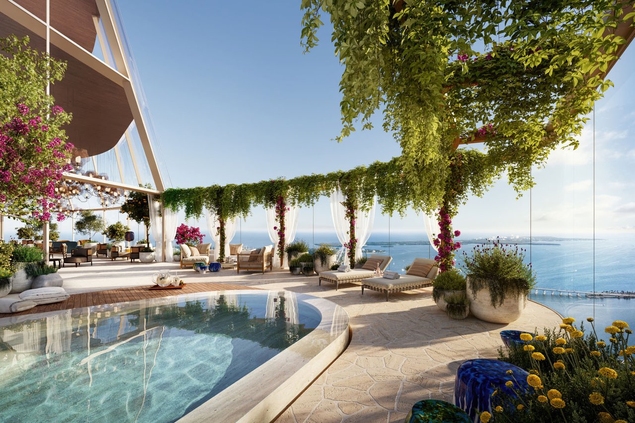 Rooftop pool terrace with lounge chairs and flowering vines overlooking the water.