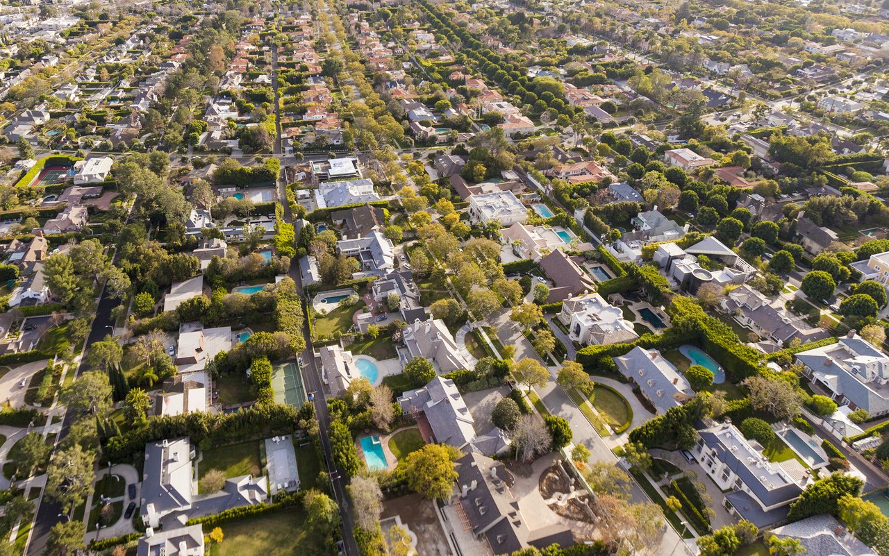 Aerial view of Tarzana homes among mature trees, with swimming pools and tree-lined streets.