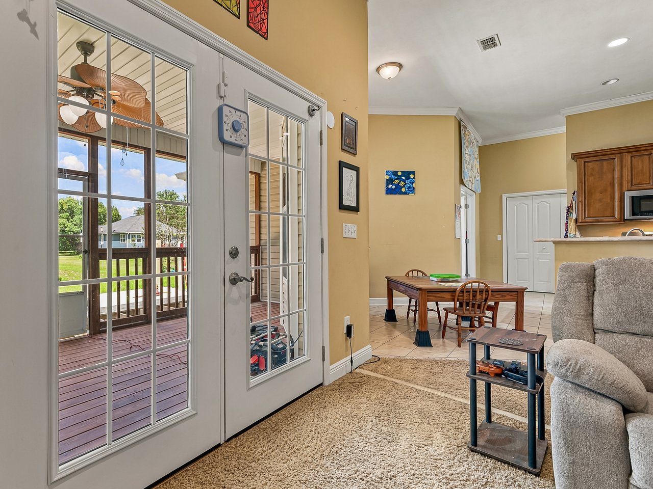 Living and dining area with French doors opening onto a covered wooden deck.