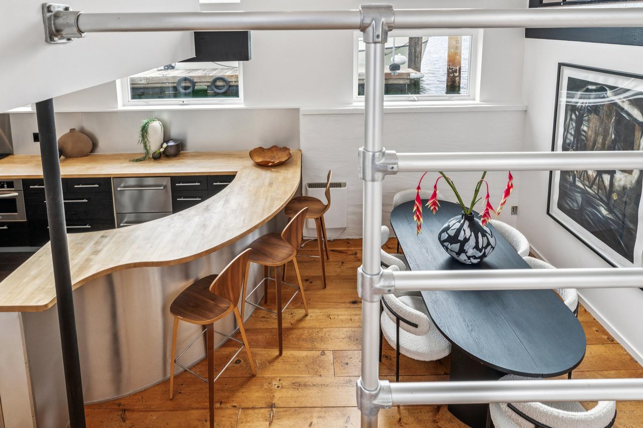 Loft kitchen and dining area with a curved wood bar and marina views through the windows.