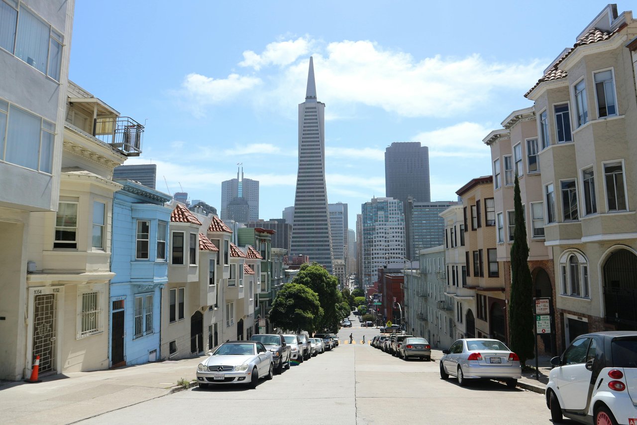San Francisco residential street with Victorian homes and city skyline — Noe Valley luxury real estate