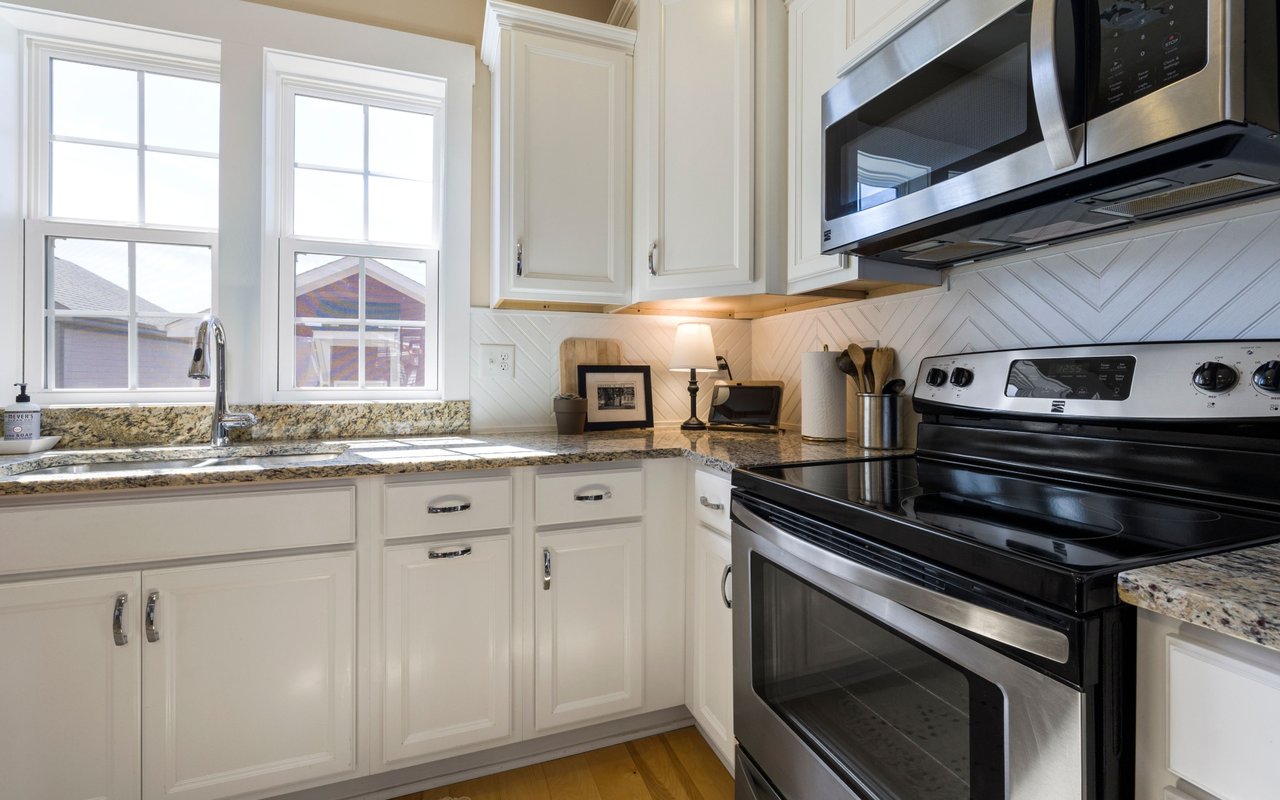 Bright kitchen with white cabinets, granite counters, and a black-and-stainless range.