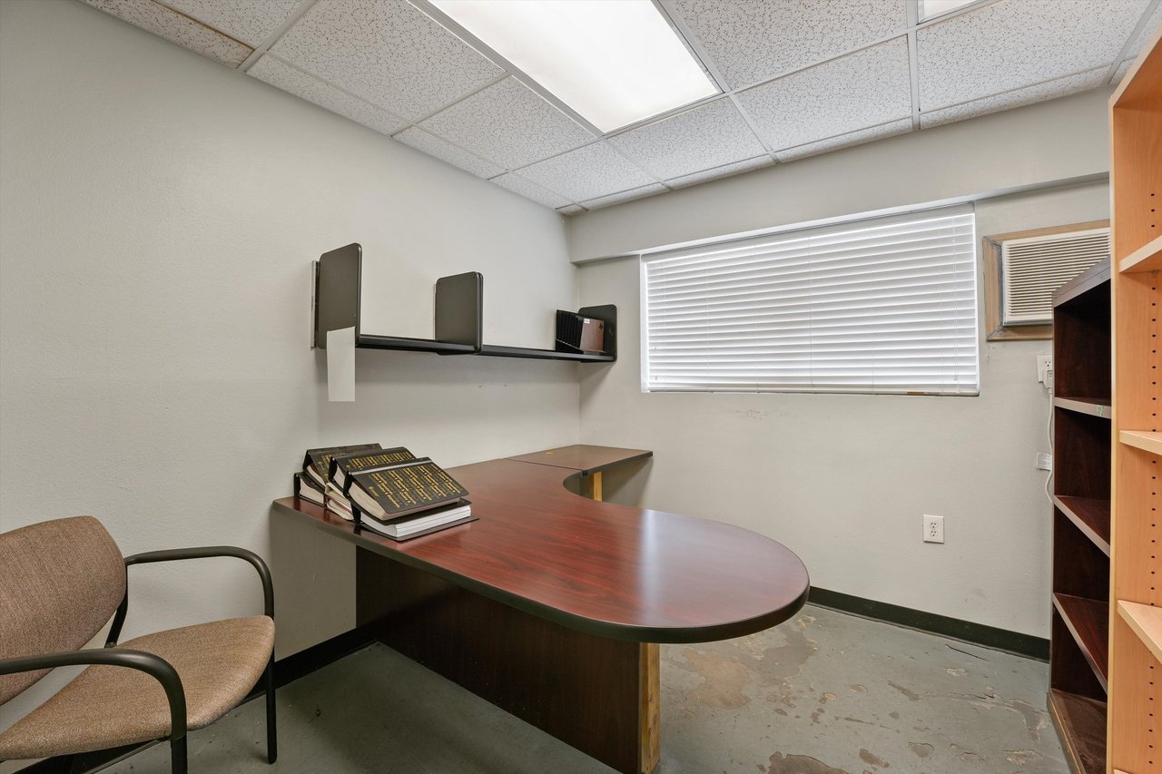 Office with a curved wood desk, wall shelf, and built-in shelving.