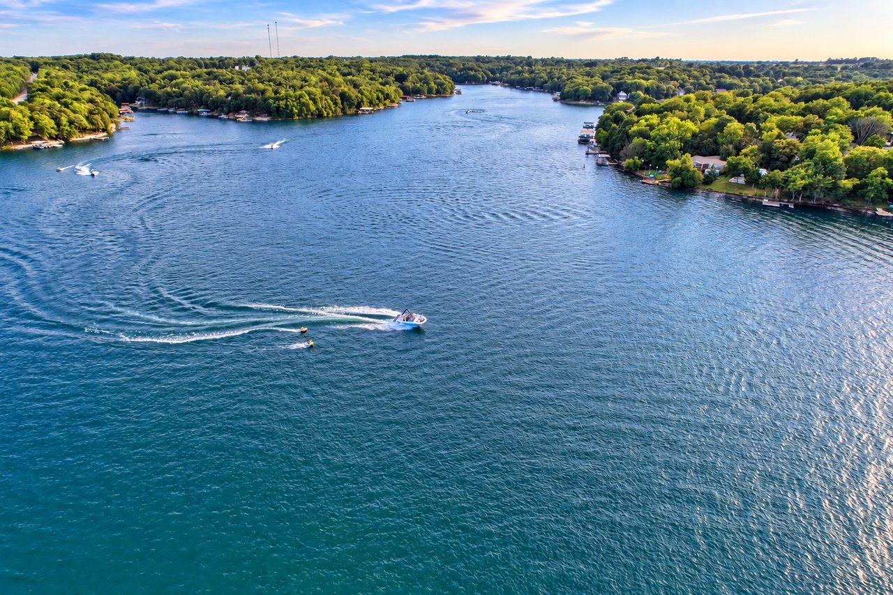 Aerial view of Lake of the Ozarks, with wooded shores, waterfront docks, and boats on the water.
