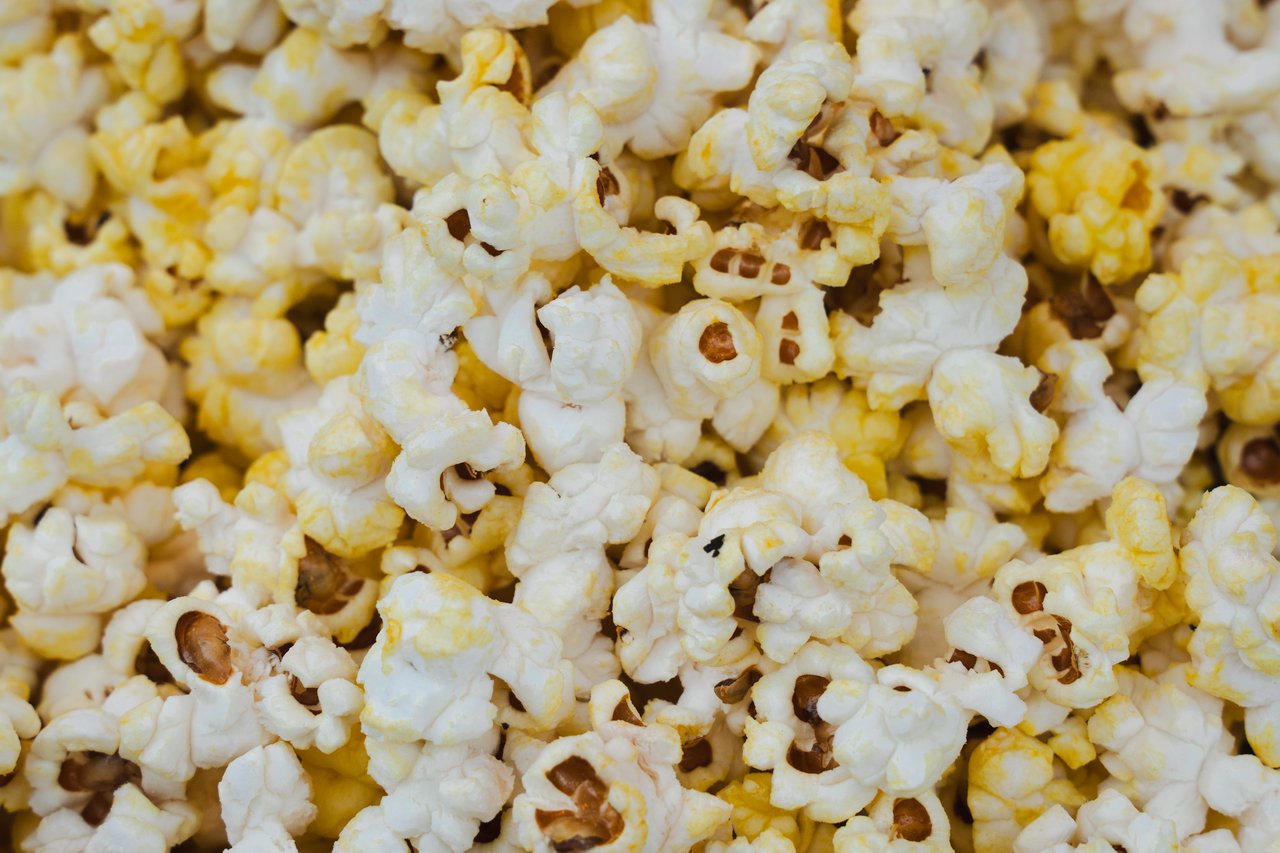 Buttered popcorn piled together, with white and yellow kernels.