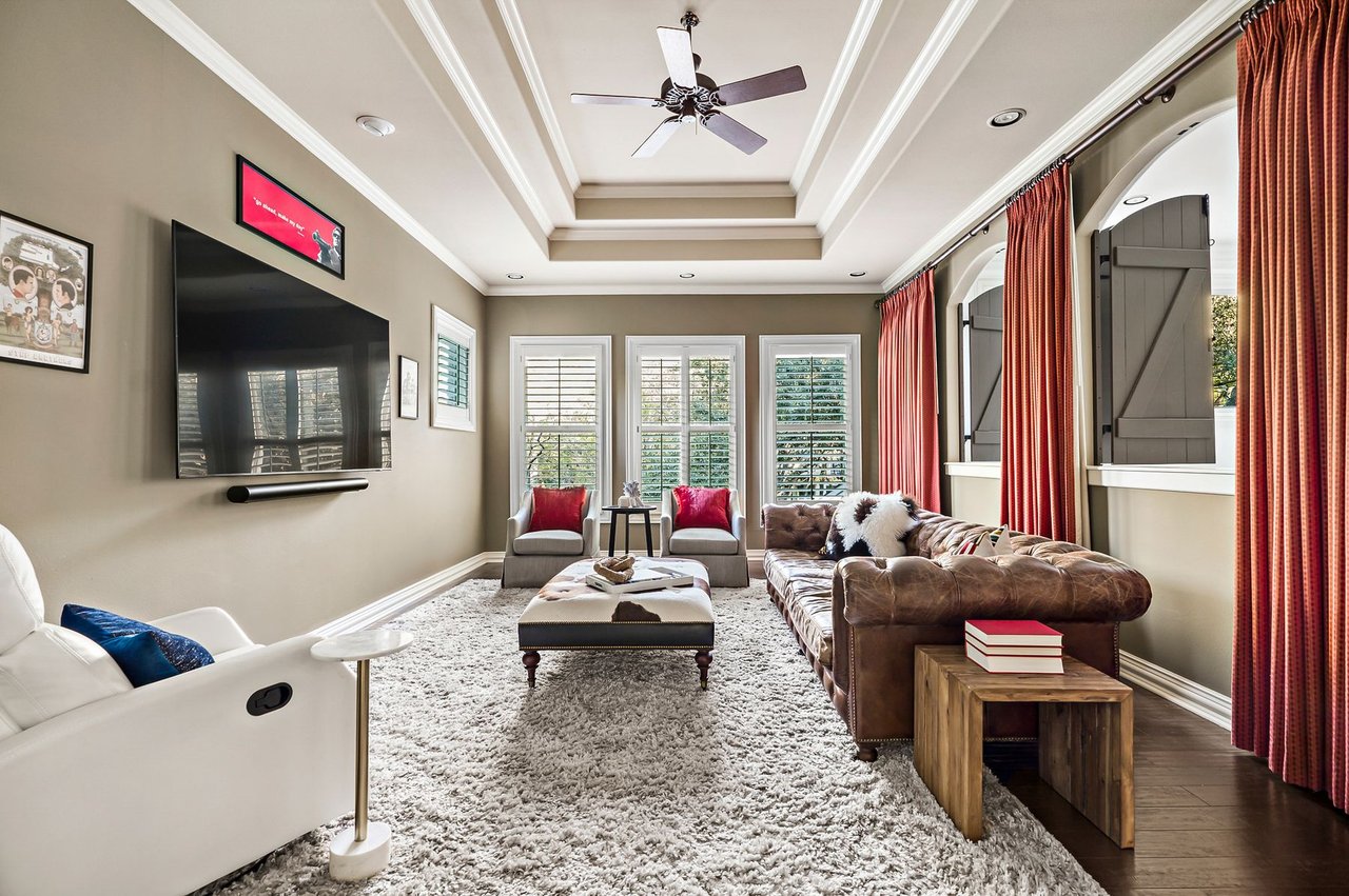 Media room with tray ceiling, leather sectional, and wall-mounted television at 5902 Saratoga Cove, Davenport Ranch, Austin, Texas.