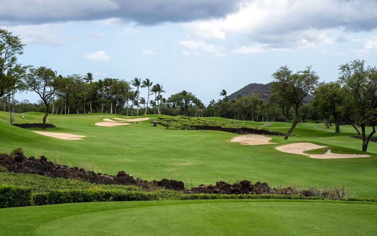 Cabo del Sol golf course with sand bunkers, palm trees, and a mountain in the distance.