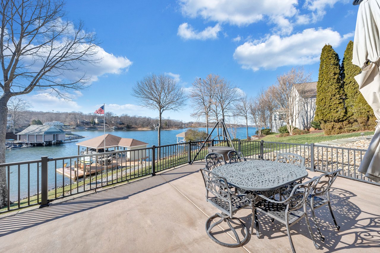 Waterfront patio with ornate dining furniture and docks across the water.