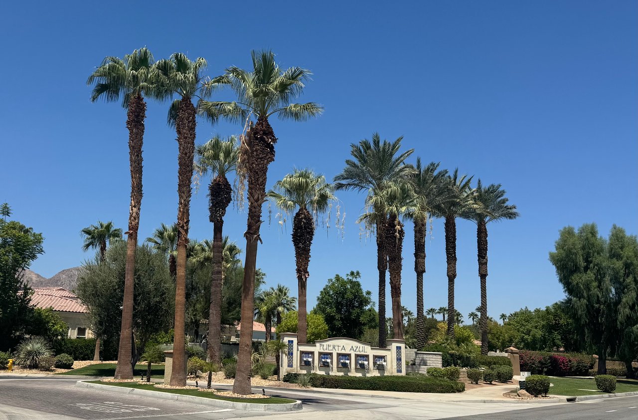 Puerta Azul community entrance with a monument sign and tall palm trees.