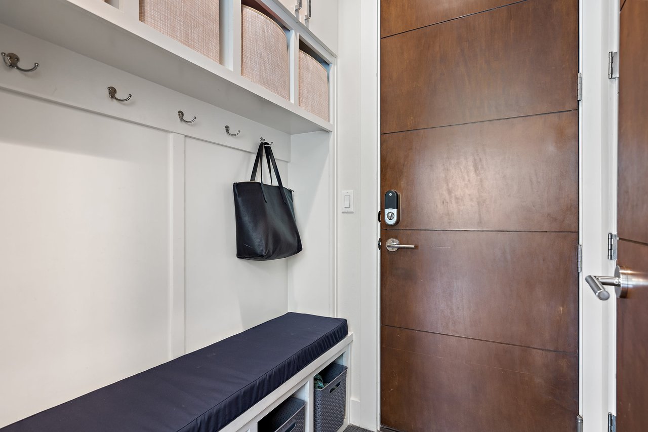 Mudroom with coat hooks, a bench, and the wood front door at 34 Margranita Crescent, Tarrytown, Austin, TX.