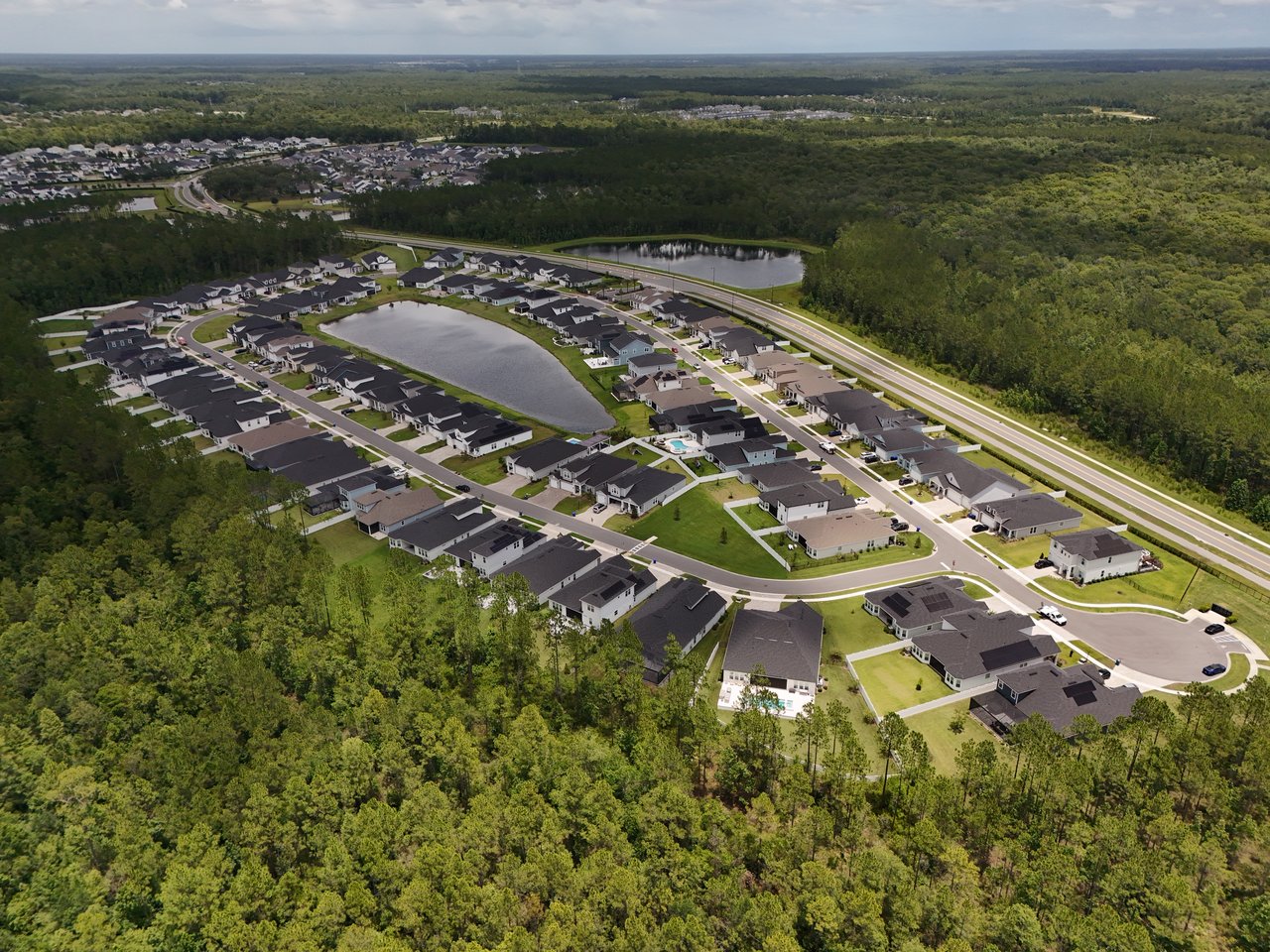 Aerial view of homes around two ponds, bordered by dense woodland.