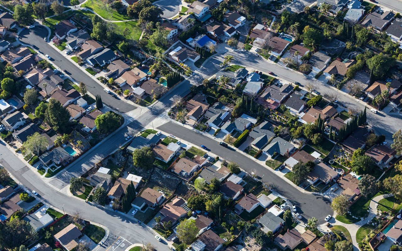 Aerial view of a residential neighborhood with detached homes and tree-lined streets.