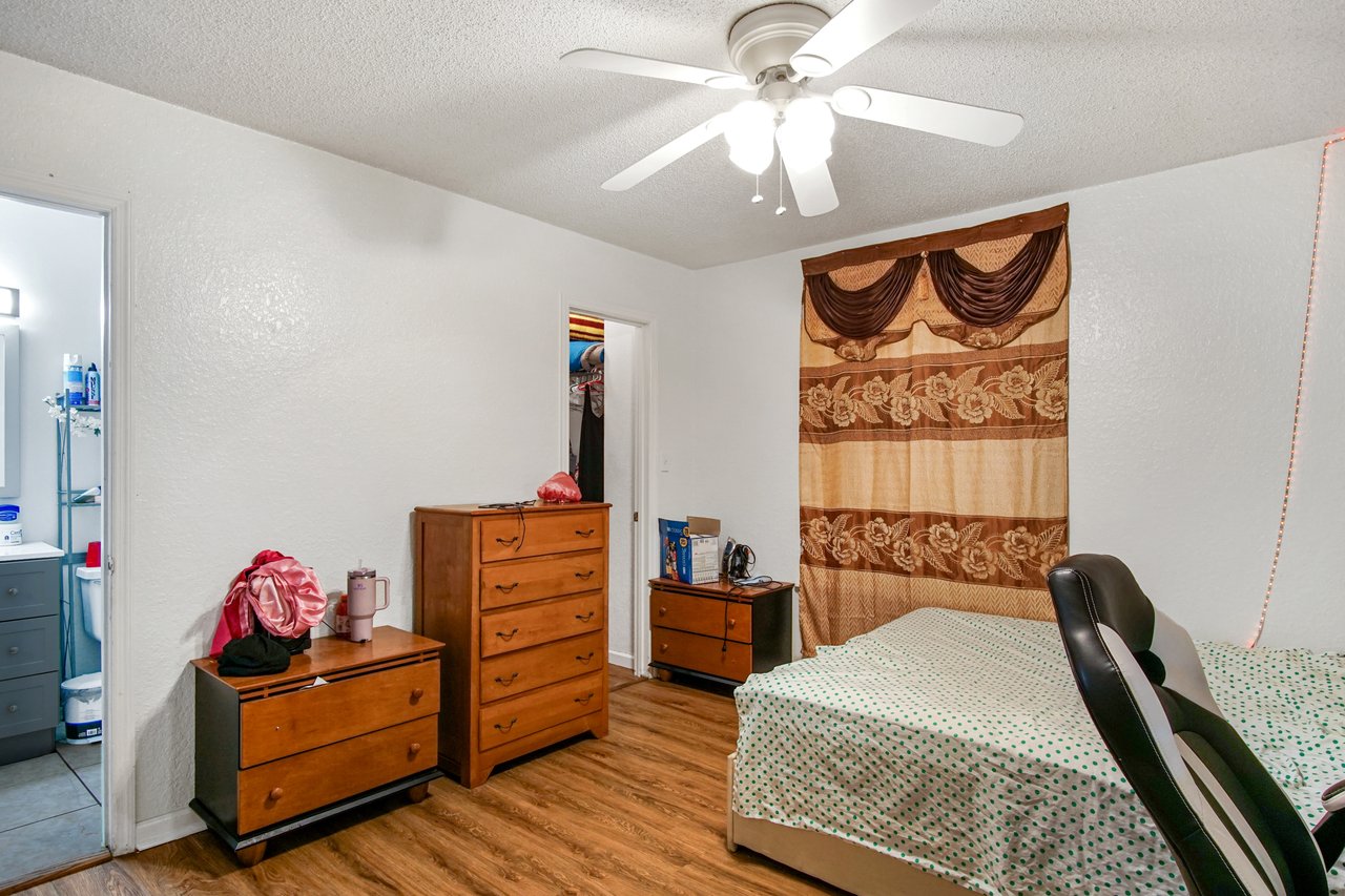 Bedroom at 2506 Nugget Lane in Tallahassee, Florida, featuring wood-look flooring, white walls, and a ceiling fan with light. The room includes multiple dressers, a bed, and access to both a closet and an adjoining bathroom.