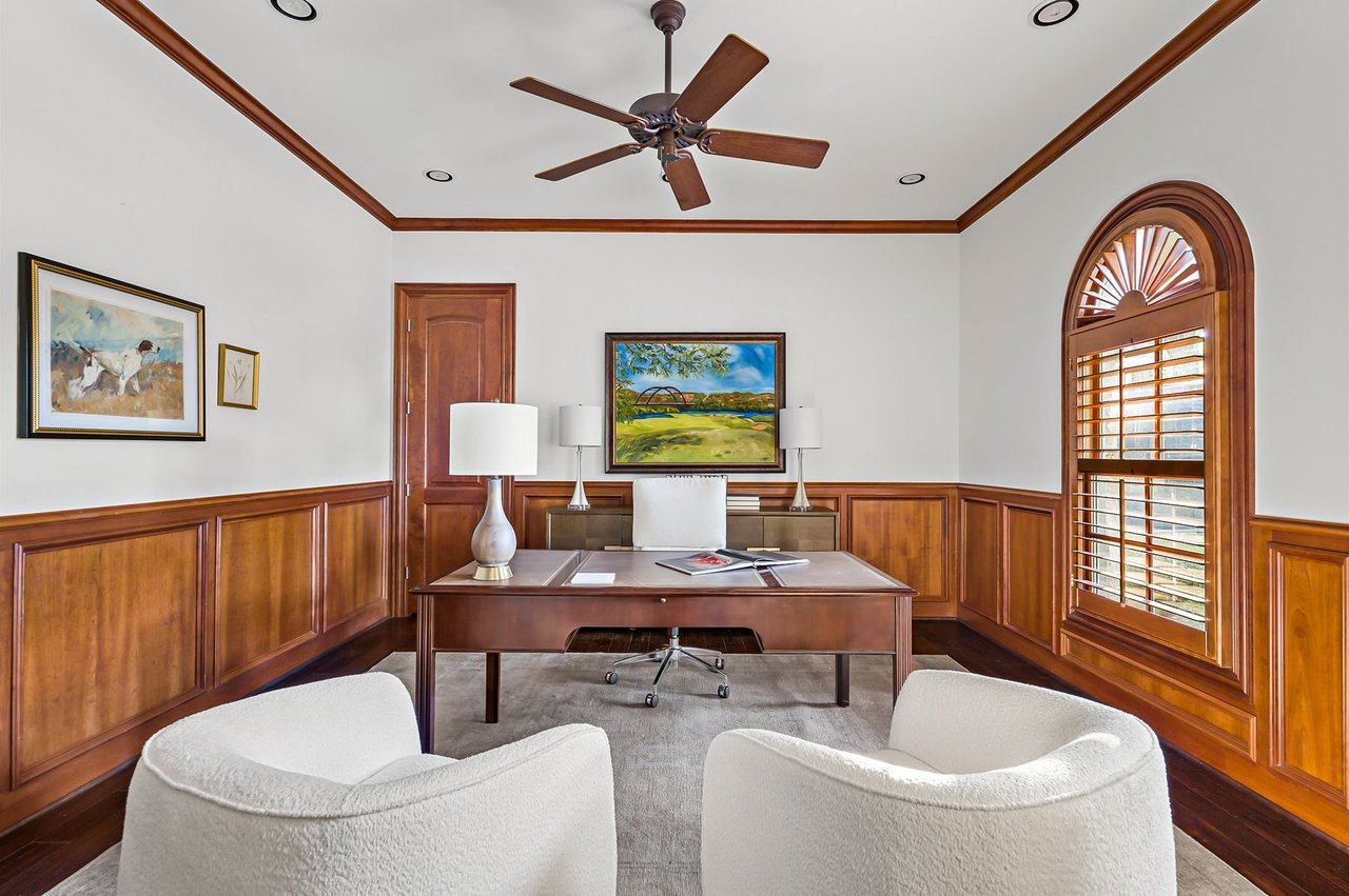 Wood-paneled study with ceiling fan and arched window at 5902 Saratoga Cove, Davenport Ranch, Austin, Texas.